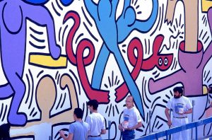 Keith Haring (il terzo da sx) con assistenti, intento all’esecuzione dell’opera murale “Tuttomondo”, Pisa 1989, © Foto Daniela Meucci, Collezione Cineclub Arsenale